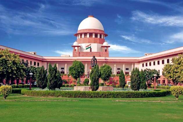 Supreme Court of India building with national flag, central dome, and green landscaped garden under a clear blue sky